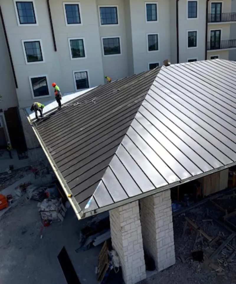 Crew installing standing seam metal roof panels on a commercial project in Neptune